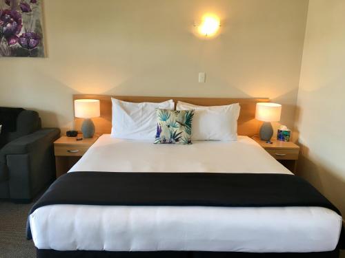 a bedroom with a large white bed with two lamps at Hacienda Motor Lodge in Palmerston North