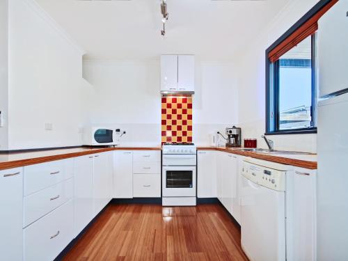 a kitchen with white cabinets and a stove top oven at Sea Devine - Port Willunga - C21 SouthCoast Holidays in Port Willunga