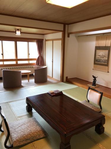 a living room with a wooden table and chairs at Hotel Higashidate in Yamanouchi