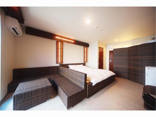 a bedroom with a bed and two wicker seats at XYZ Private Spa and Seaside Resort in Shirahama