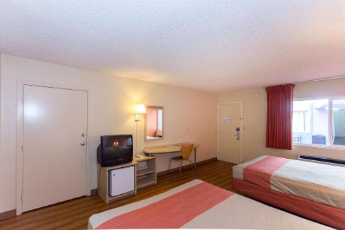 a hotel room with two beds and a desk with a television at Cathedral Hill Hotel in San Francisco