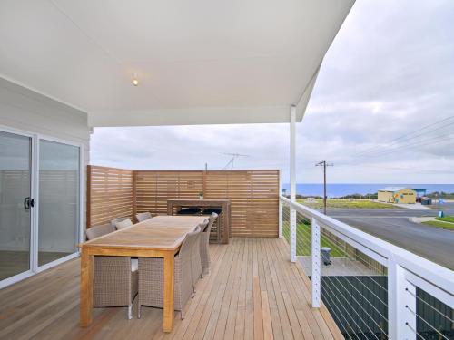 a deck with a table and chairs on a balcony at Seas the Day - Aldinga Beach - C21 SouthCoast Holidays in Aldinga Beach