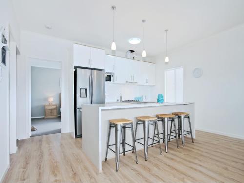a kitchen with white cabinets and bar stools at Seas the Day - Aldinga Beach - C21 SouthCoast Holidays in Aldinga Beach