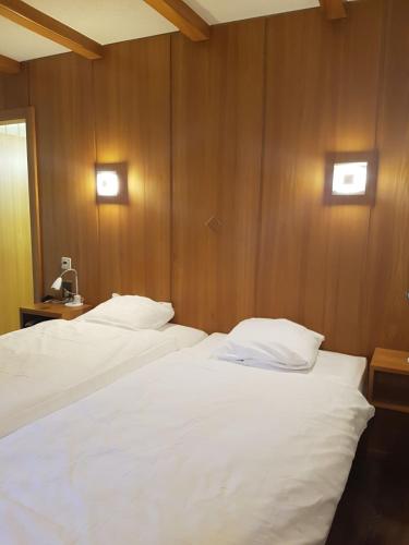 two white beds in a room with wooden walls at Motel des Sports Martigny in Martigny-Ville