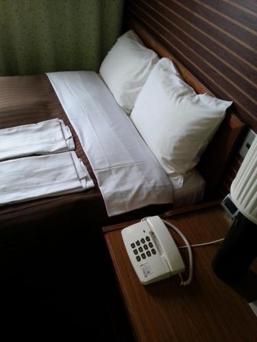 a room with a bed with a phone on a table at Hotel Sun Hitoyoshi in Hitoyoshi