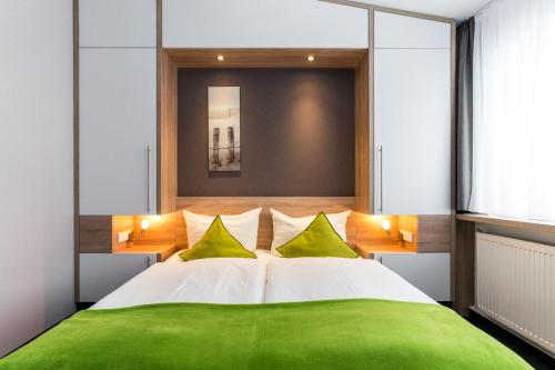 a bedroom with a green and white bed with yellow pillows at Pension Alabama in Warnemünde