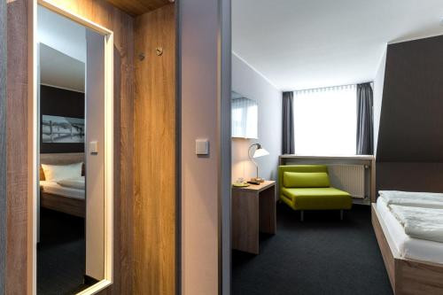 a hotel room with a green chair and a bedroom at Pension Alabama in Warnemünde