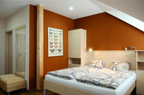 a bedroom with a bed with an orange wall at Restaurace Obůrka in Blansko