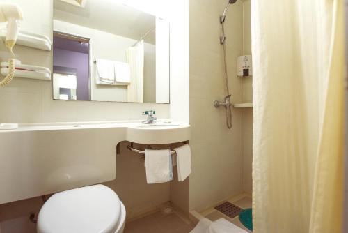 a bathroom with a toilet and a sink and a mirror at Jinjiang Inn Tongliao Jianguo Road in Tongliao