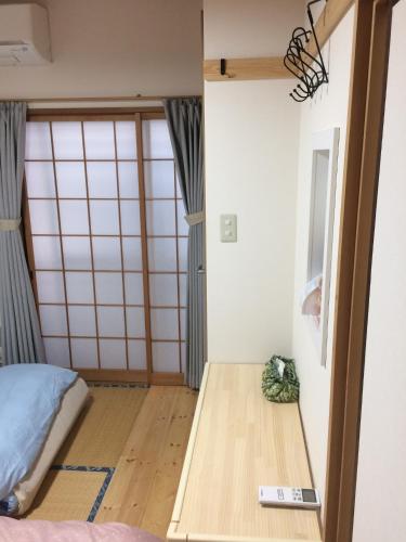 a room with a bed and a wooden floor at Ryokoheya Tenrokukan in Osaka