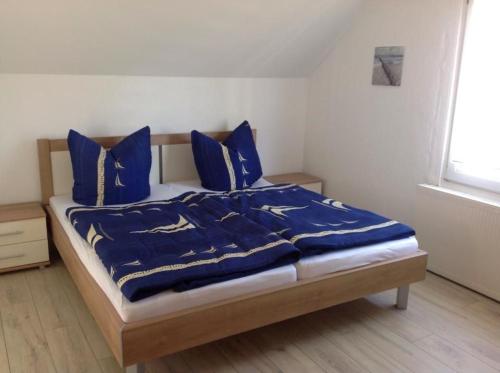 łóżko z niebieskimi kocami i poduszkami w sypialni w obiekcie Haus Irma w Zingst