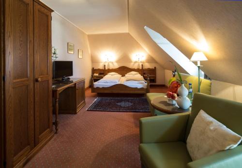 um quarto de hotel com uma cama, um sofá e uma televisão em Hotel und Weinhaus Zum Krug em Eltville