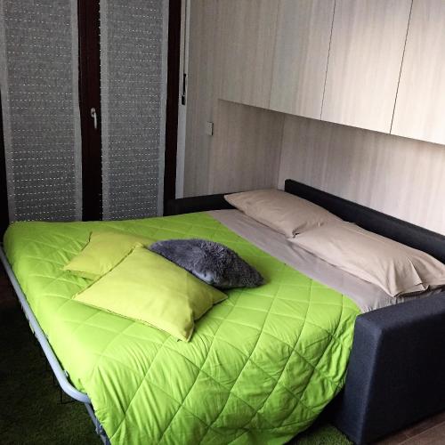 a bed with green sheets and pillows on it at Appartamento Morena CIR 0043 in Aosta