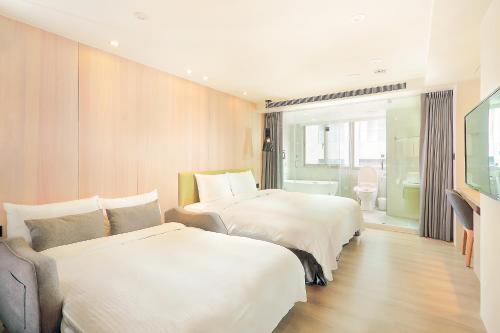 a hotel room with two beds and a television at Green Hotel - West District in Taichung