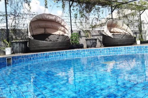 a swimming pool with two chairs and a swimming pool at Hotel Grand Zuri Muara Enim in Muaraenim