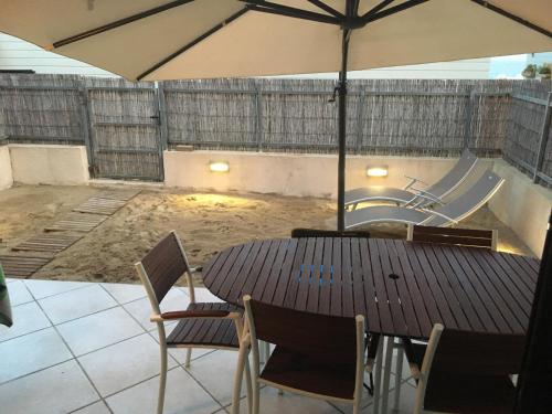ラ・クロワ・ヴァルメにあるAppartement face à la merのパティオに置かれたテーブルと椅子、そして傘