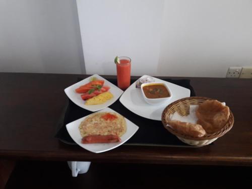 a table with plates of food and a basket of food at Port View City Hotel in Colombo