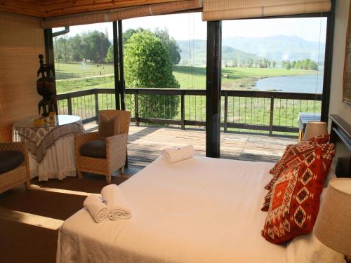 a bedroom with a bed and a large window at Sani Valley Nature Lodges in Himeville