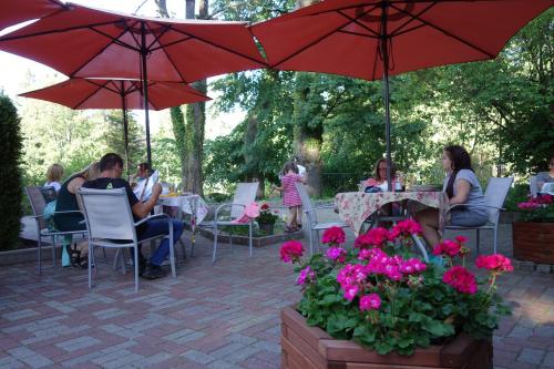 Un grupo de personas sentadas en mesas bajo sombrillas. en Hotel Magnes, en Szklarska Poręba