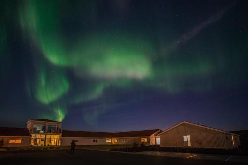 a person standing in front of a building under the aurora at Northern Light Inn in Grindavík