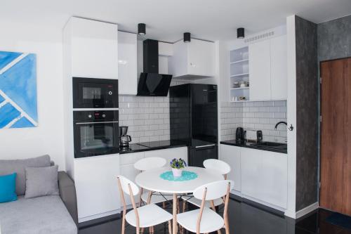 a kitchen and living room with a table and chairs at Apartament Winogrady Hawelańska in Poznań