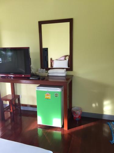 una nevera verde junto a un escritorio con espejo en Poon Suk Hotel Kabin Buri, en Kabin Buri