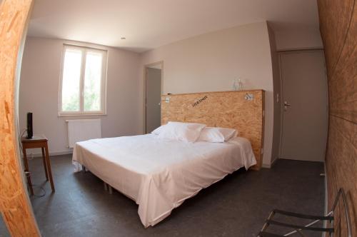 a bedroom with a bed with white sheets and a window at Le Jardin de la Reyssouze in Gorrevod