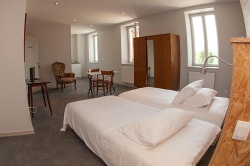 a bedroom with two beds and a table and chairs at Le Jardin de la Reyssouze in Gorrevod