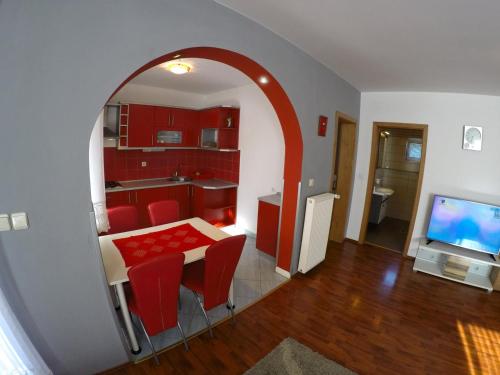 a kitchen with red cabinets and a table with red chairs at Apartments and Rooms Rea in Sveti Martin na Muri