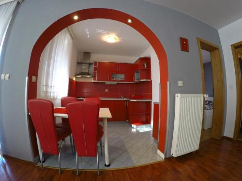 a kitchen with red cabinets and a table with red chairs at Apartments and Rooms Rea in Sveti Martin na Muri