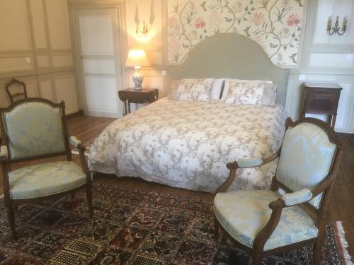 a bedroom with a bed and two chairs at Château Ville Voisin in Augan