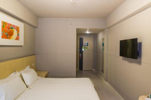 a hotel room with a bed and a flat screen tv at Jinjiang Inn Select Harbin West Station Lijiang Road in Harbin