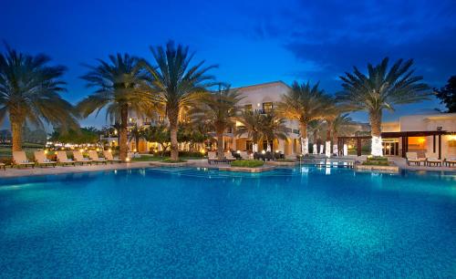 a large swimming pool with palm trees and palm trees at Address Montgomerie in Dubai
