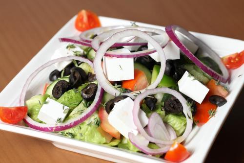a salad with onions and olives on a white plate at Jazan Inn Hotel in Jazan