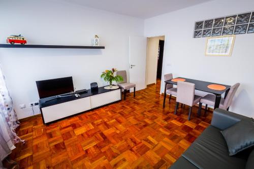 a living room with a wooden floor and a table and chairs at Apartamento Vista Oceano in Caniço
