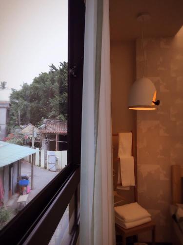 a room with a window with a chair and a lamp at Ho.Me-Easyhouse in Tainan