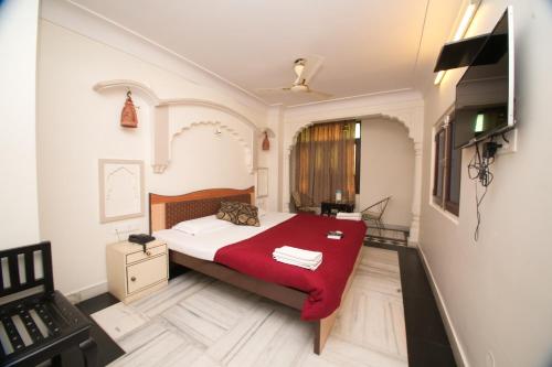 a bedroom with a bed with a red blanket at Hotel Kalyan in Jaipur