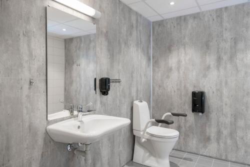 a bathroom with a sink and a toilet and a mirror at Fast Hotel Svolvær in Svolvær