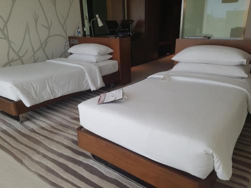 a hotel room with two beds and a mirror at Taj Yeshwantpur Bengaluru in Bengaluru