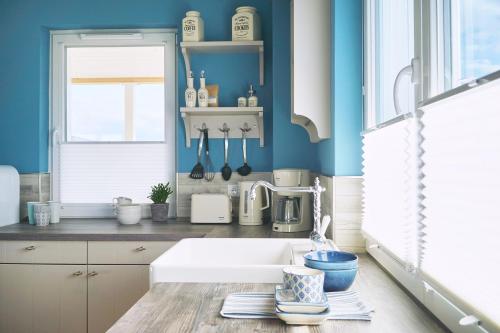 a kitchen with blue walls and a white sink at Beach Apartments Heiligenhafen in Heiligenhafen