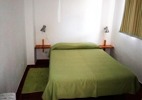 Cama verde en habitación con ventana en Parque de Campismo Orbitur Valverde, en Luz