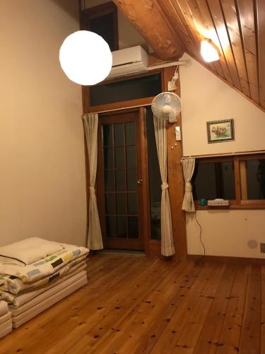 a room with a bed and a lamp on a wooden floor at Canadian Loghouse Inn AzuminoYujin in Azumino
