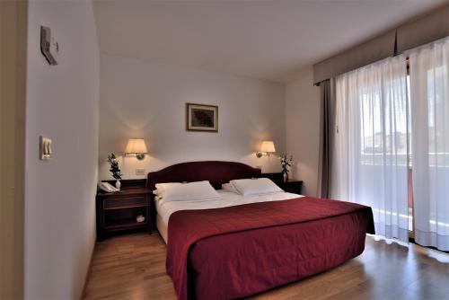 Hotel Hannover في غرادو: غرفة نوم بسرير كبير ونافذة