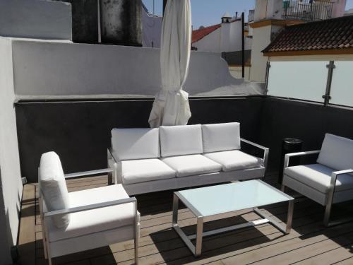 een witte bank en 2 stoelen en een tafel op een balkon bij Le Petit Paris in Sevilla