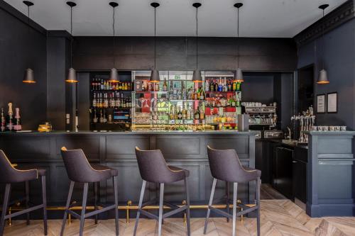 a bar with four stools in front of a counter at Excelsior Chamonix Hôtel & Spa in Chamonix-Mont-Blanc