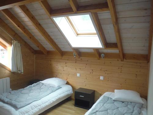 two beds in a room with a skylight at Les airelles in Gérardmer