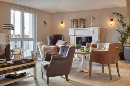 a living room with chairs and a table and a fireplace at Beach Apartments Heiligenhafen in Heiligenhafen