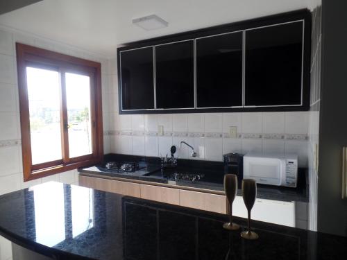 a kitchen with black counter tops and a microwave at Flat ao lado do Shopping in Santa Cruz do Sul
