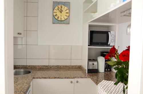 a kitchen with a sink and a clock on the wall at Calypso Oasis Apartments in Puerto Rico de Gran Canaria