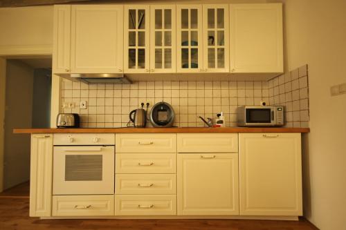eine Küche mit weißen Schränken und einer Mikrowelle in der Unterkunft Apartmány Scharffenberg in Banská Štiavnica